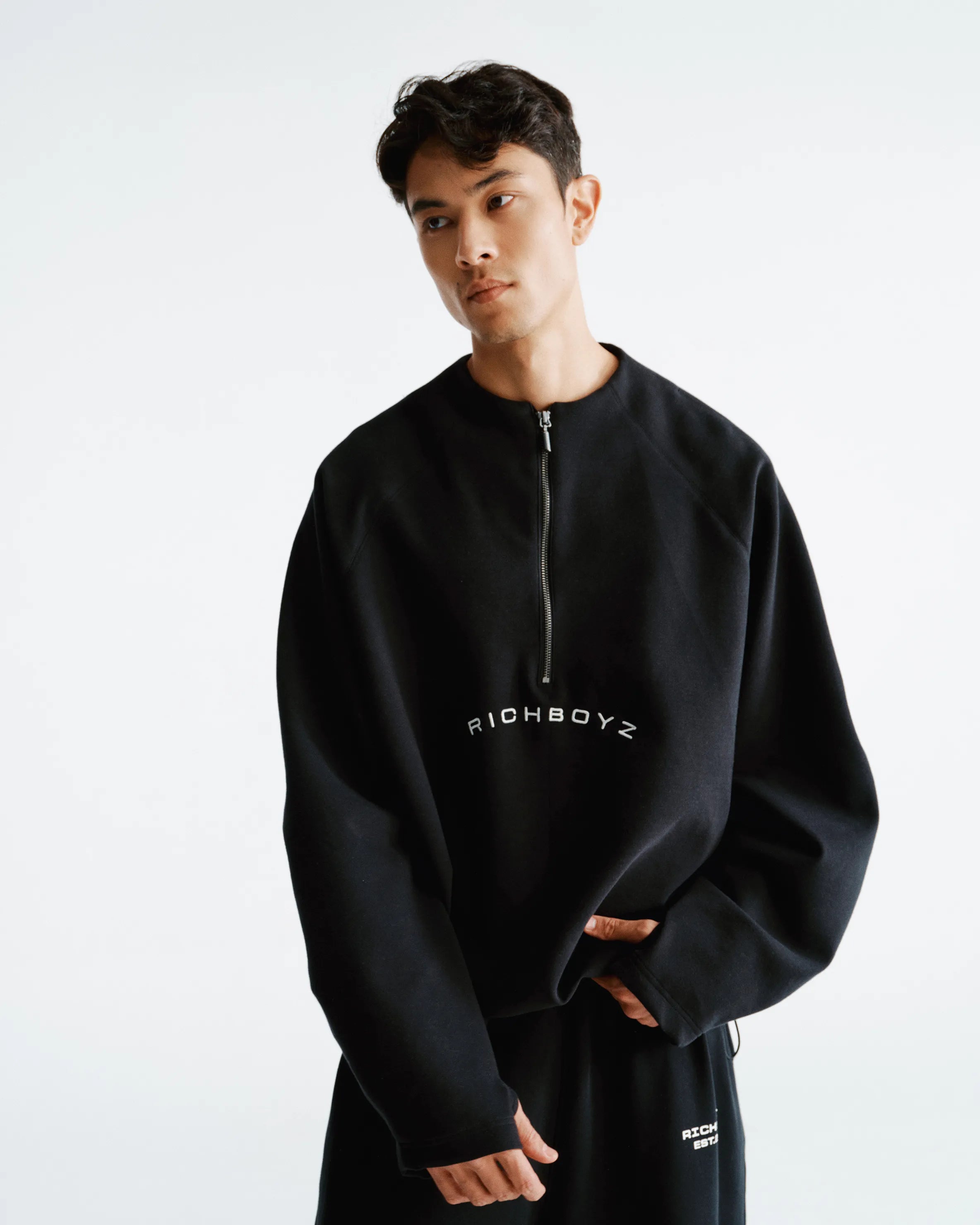 Person wearing a black 'RICHBOYZ' sweatshirt on a white background