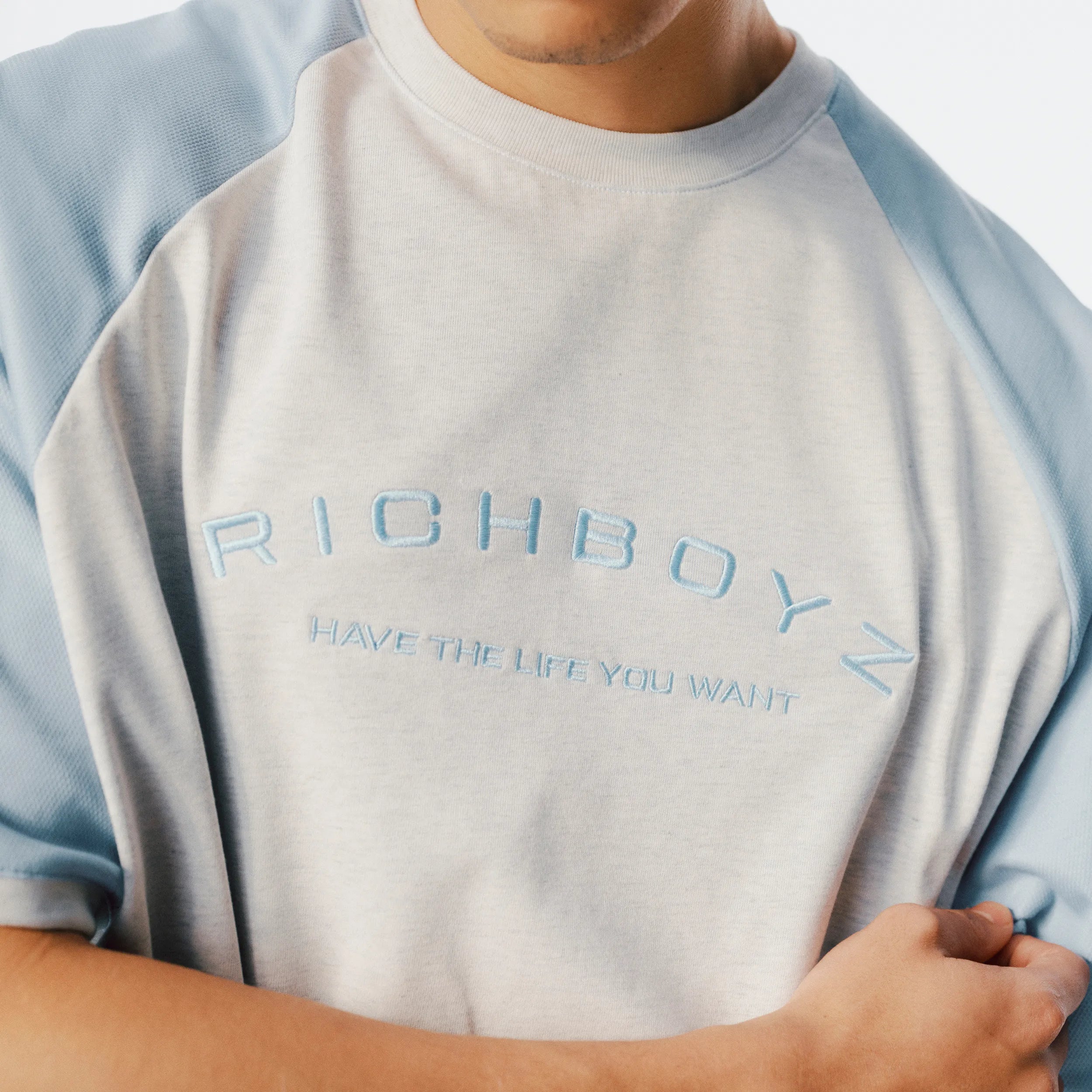 Close-up of Raglan Tee soft fabric texture and raglan sleeve seam detail in Heather Gray